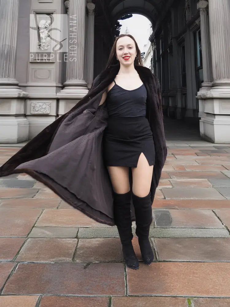 Dark brown mink fur coat with open tuxedo front and flared hem over a dress