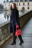 "Midnight Iris" navy sheared beaver coat in side profile, flared hem, red cuffs
