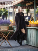 Black mink long coat with open front and angled hem, worn with knee boots
