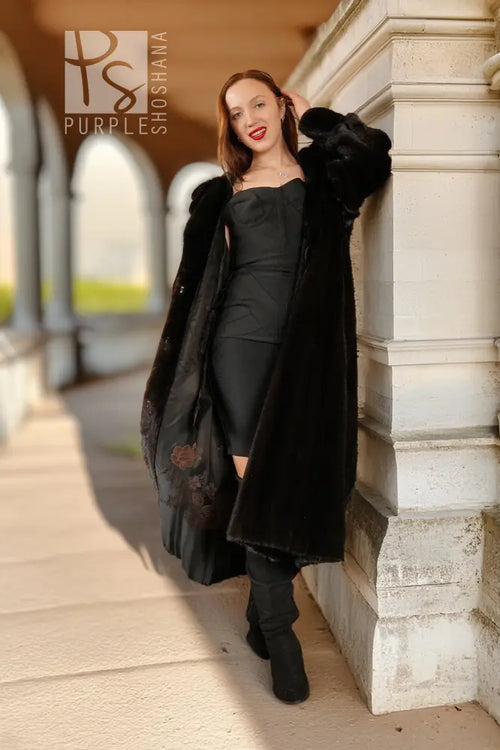 Black hooded mink coat draped open, front view near doorway