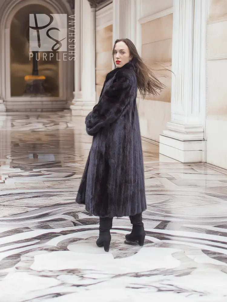 Black mink fur long coat with textured fur trim and tall neckline, side view.