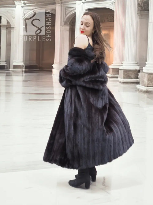 Black mink fur A-line coat with high collar and gathered fur texture, front three-quarter view.