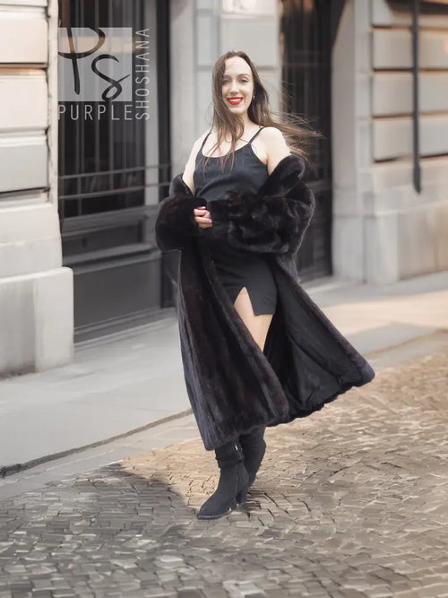 Black mink fur coat with wide off-shoulder design, worn over black dress