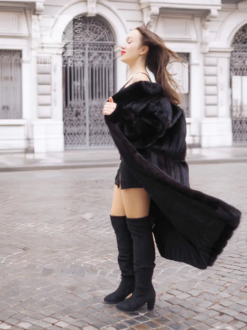Black mink fur coat with long draped sleeves, worn over black dress and boots