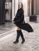 Black mink fur coat with high neckline, knee-length hem, and long draped sleeves.