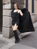 Black mink fur coat with off-shoulder silhouette and long sleeves, side view over dress
