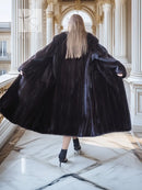 Black mink coat, back view with flared hem and long wide fur sleeves.