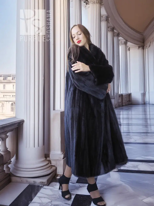 Black mink coat with long sleeves and plush collar, standing with arms folded
