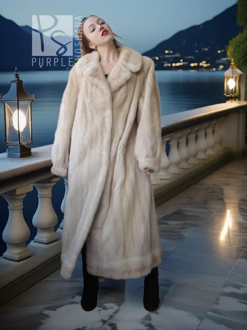 Cream fur coat with pointed lapels, long length, and relaxed fit over boots.