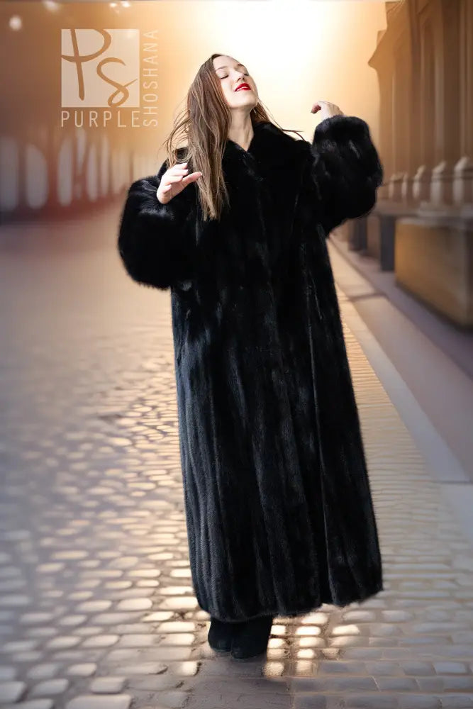 Black mink full-length coat with high collar and button front; held mid-walk pose.