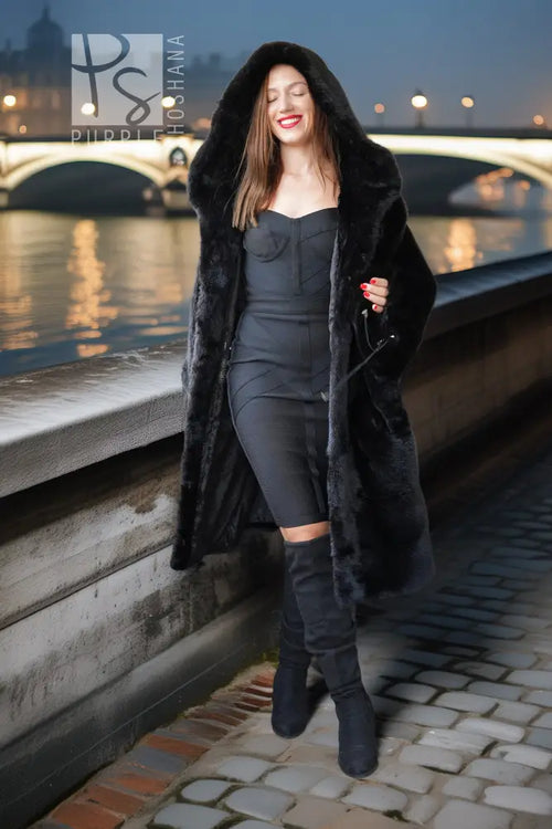 Black hooded mink coat with open front and long fur sleeves, worn with dark leggings.