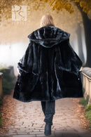 Black hooded mink coat from behind, full skirt flare over dark leggings