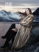 Long fur coat in striped tan and dark, side sitting pose, open front and wide sleeves.