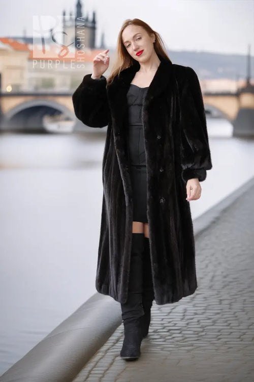 Black mink coat with button front and thick collar, walking pose with dark boots.
