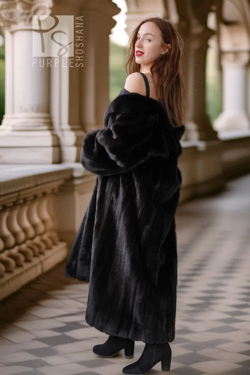 Black fur coat with voluminous sleeves and open shoulder design, side view