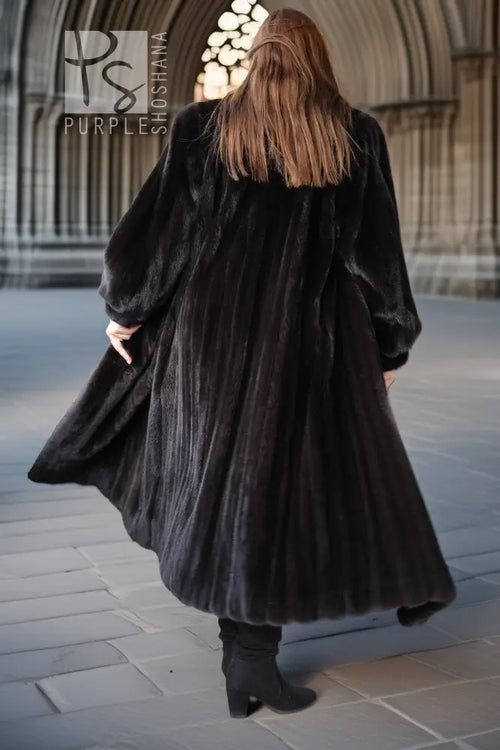 Back view of a black mink coat with flared skirt and wide fur sleeves.