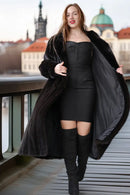 Black mink coat with voluminous sleeves and draped front, front view with boots.