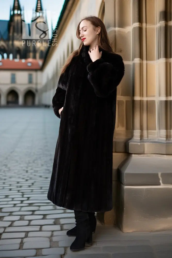 Black fur coat with button-front, long sleeves, mid-calf length, standing near steps.