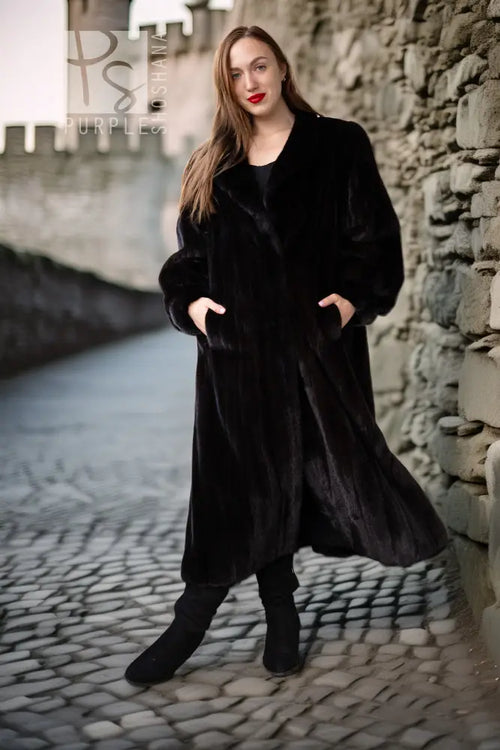 Black fur coat with button-front, long sleeves, mid-calf length, walking view.