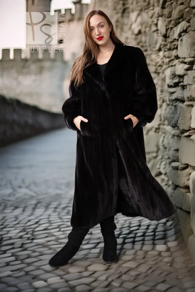 Black fur coat with button-front, long sleeves, mid-calf length, walking view.