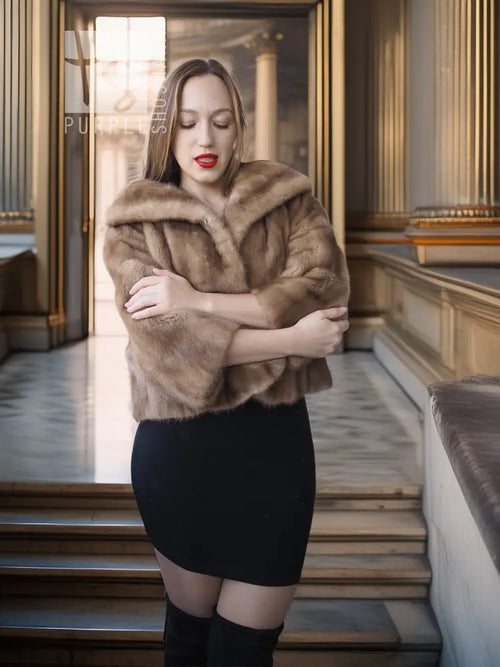 Vintage mink opera jacket with hood, tan fur, arms crossed showing short sleeves.