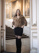 Tan mink fur opera jacket with hood, cropped front view over a black mini dress