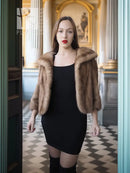 Vintage mink opera jacket with hood, tan fur, worn open over a black dress.