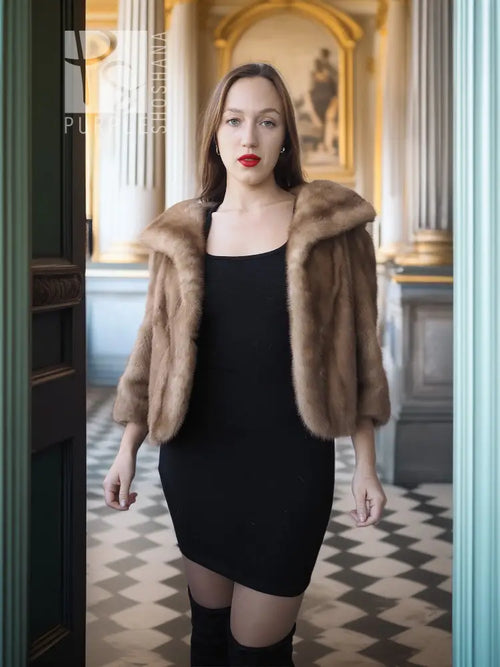 Vintage mink opera jacket with hood, tan fur, worn open over a black dress.