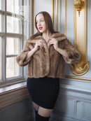 Vintage mink opera jacket with hood and tan fur, hands holding front lapels.