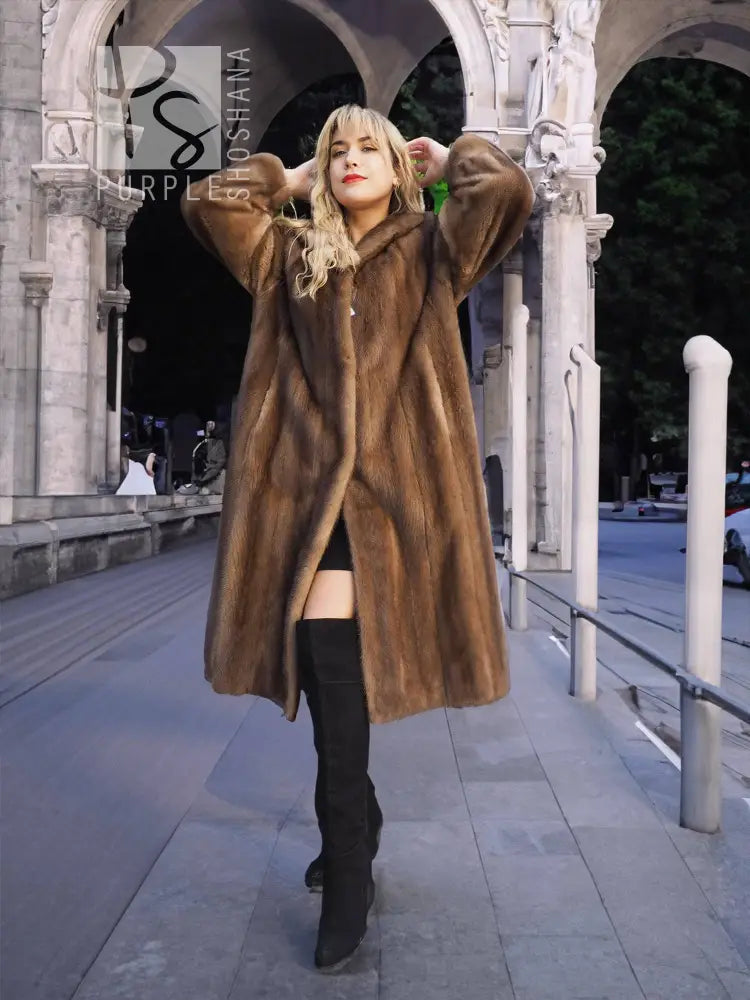 Women's brown mink fur coat with plush collar, hands up styling, knee-length.
