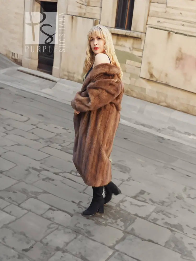 Brown mink fur coat with hood and long sleeves, side view.