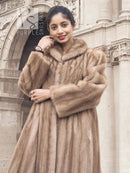 Light brown mink fur coat with hood, close-up of collar and folded arm.
