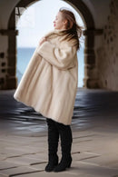 Pearl mink swing coat with hood, cream fur, full flared hem over tall boots