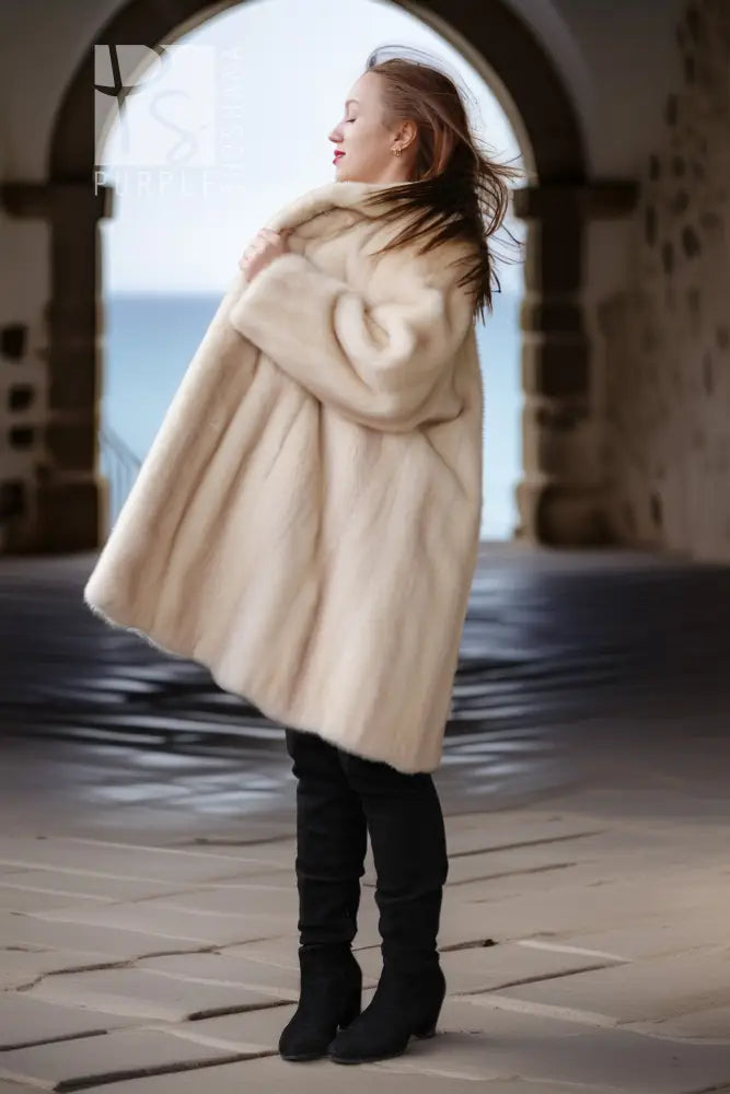Pearl mink swing coat with hood, cream fur, full flared hem over tall boots