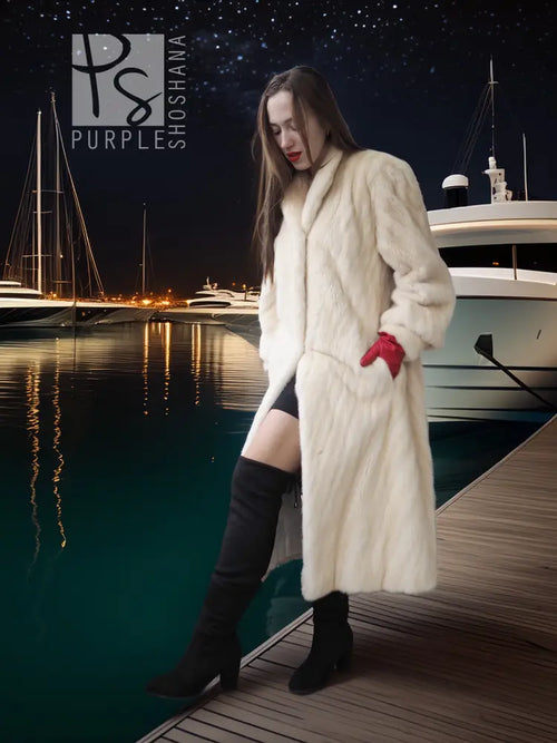 Cream long fur coat with diagonal design and red knit cuffs, side pockets.