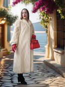 Cream long fur coat with diagonal design, stand collar, red knit cuffs, side pockets.
