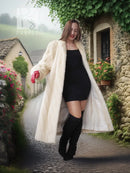 Cream fur coat with open front and draped hem, standing outdoors in profile