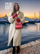 Cream fur coat with open front and shawl collar; holding red handbag