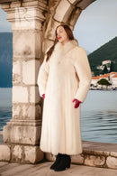 White fur coat with red cuffs and high collar, long sleeves, outdoor waterfront setting