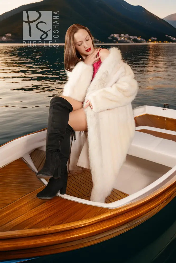 White fur coat with red cuff trim, styled on a boat with black boots