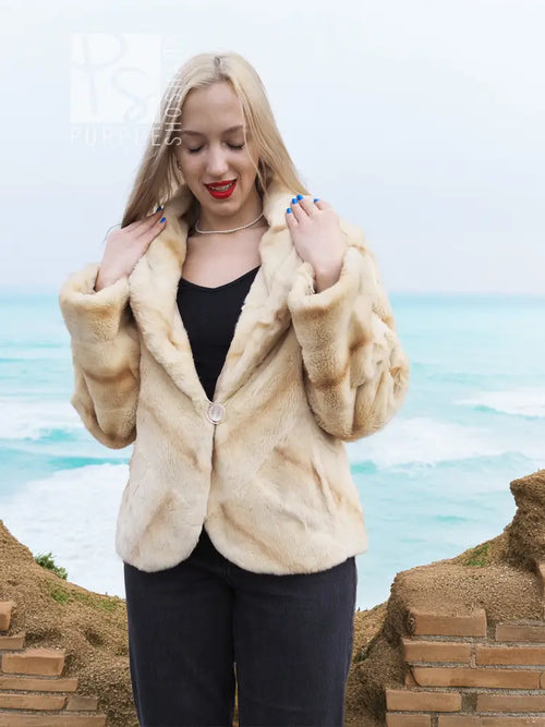 Light beige fur jacket with open V front and thick sleeves, worn with dark pants