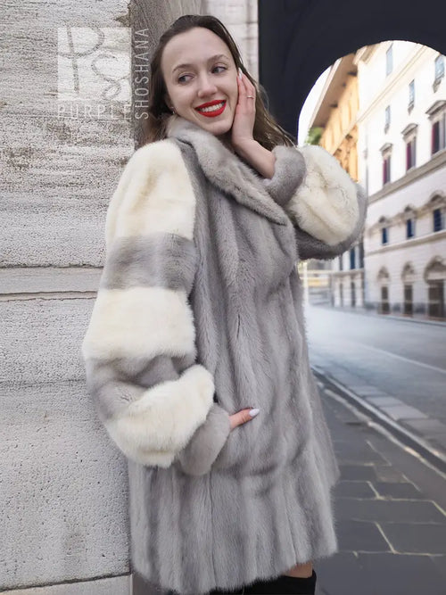 Mink fur coat with striped light sleeve panels and wide collar, worn mid-length.