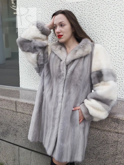 Mink fur coat in light gray with wide collar and cream fur cuffs, close side view