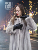 Grey mink fur coat with hood and front button closure, black gloves held up.