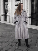 Grey mink fur coat with hood and long sleeves, black cuff accents.