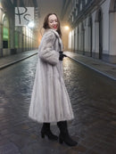 Grey mink fur coat with hood and long skirt-like length, side view.