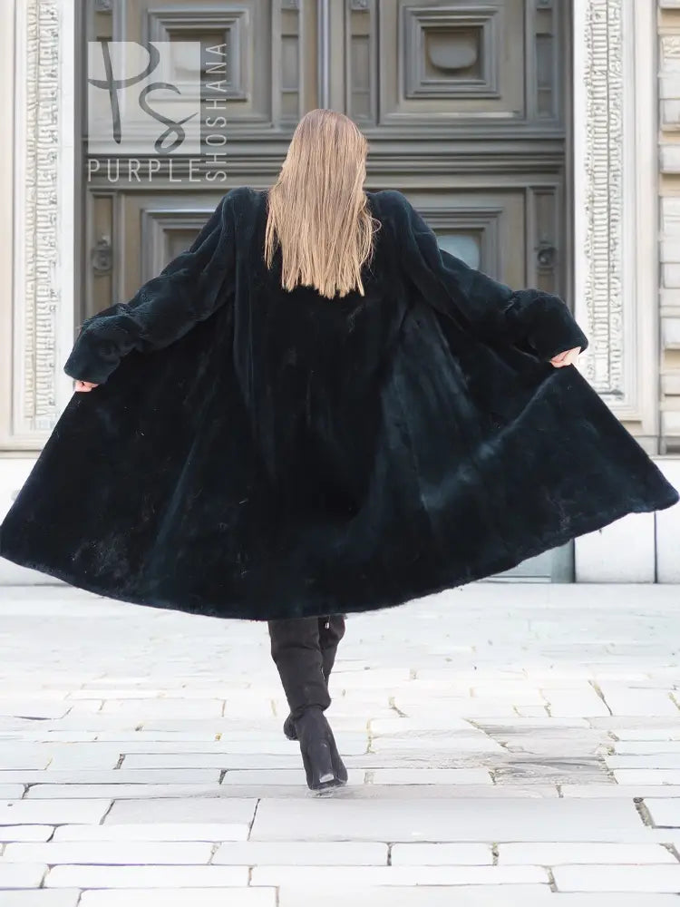 Back view of dark mink fur coat with flared skirt and long sleeves.