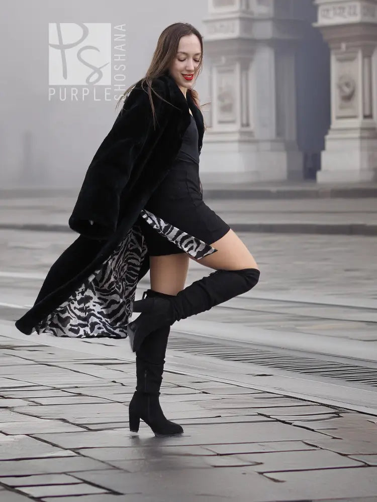 Black mink fur coat worn open, showing patterned inner lining and tall boots.