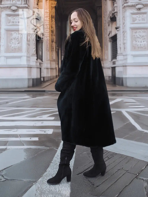 Dark mink fur coat with long sleeves and straight hem, side view on street.