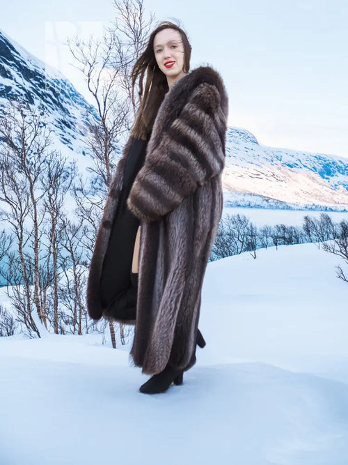 Three-quarter view of long hooded dark brown fur coat with wide collar and sleeves.
